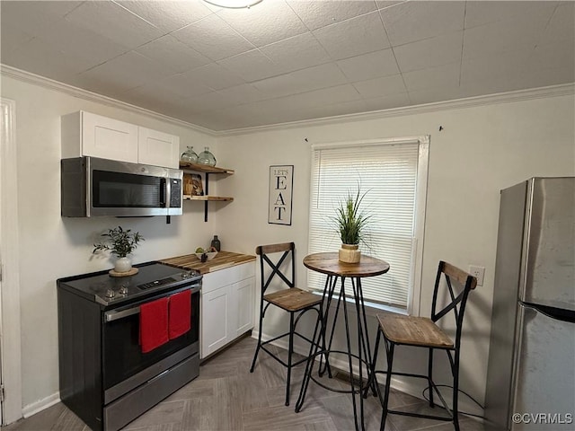 kitchen with stainless steel appliances, white cabinets, ornamental molding, and wood counters