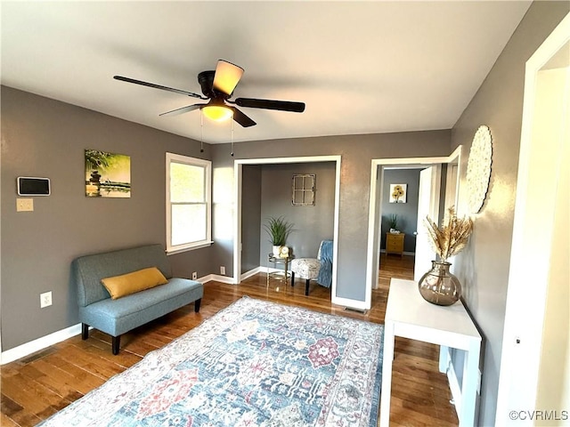 living area featuring visible vents, wood finished floors, a ceiling fan, and baseboards