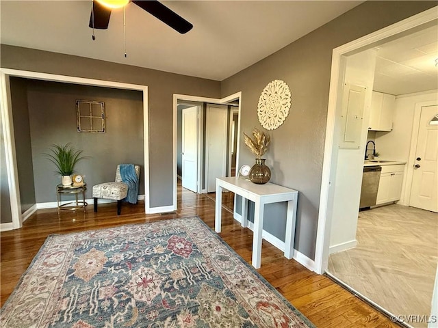 living area with ceiling fan, light wood-type flooring, and baseboards