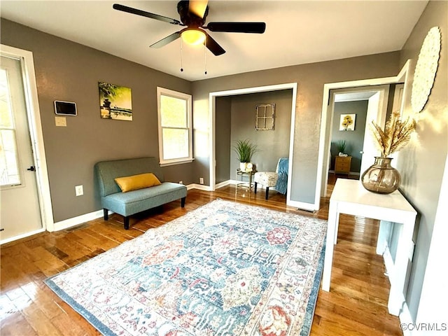 sitting room with a ceiling fan, baseboards, visible vents, and hardwood / wood-style floors