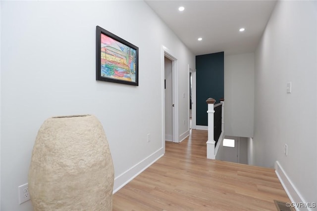 hallway with baseboards, light wood finished floors, an upstairs landing, and recessed lighting