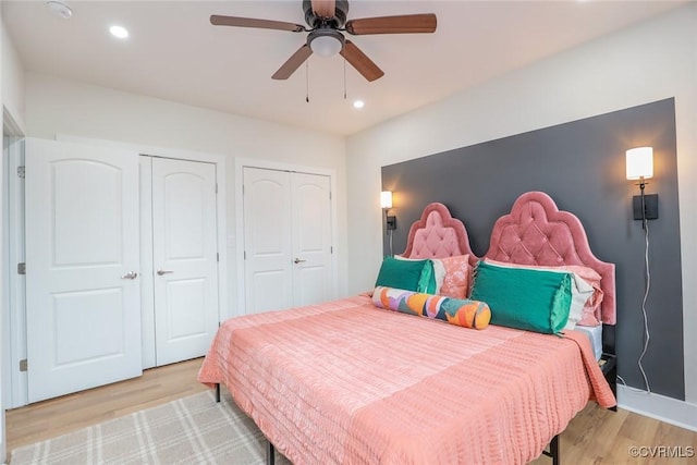 bedroom with light wood-type flooring, two closets, and recessed lighting