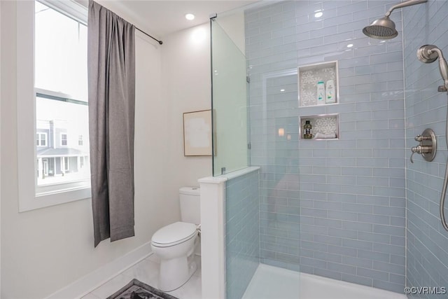 bathroom featuring toilet, baseboards, and a tile shower