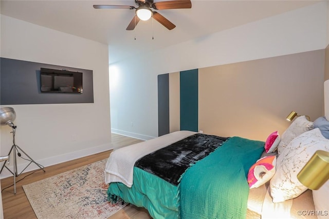 bedroom with a ceiling fan, baseboards, and wood finished floors