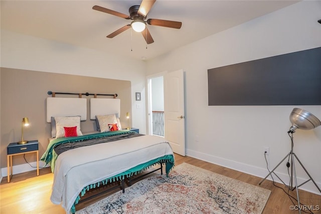 bedroom with a ceiling fan, baseboards, and wood finished floors