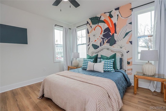 bedroom featuring ceiling fan, baseboards, and wood finished floors