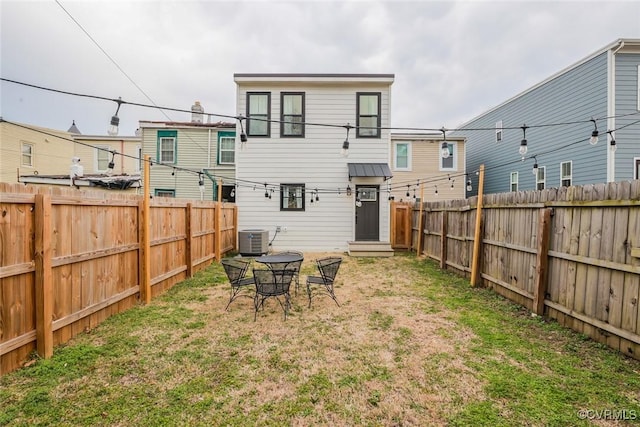 back of property featuring a fenced backyard, cooling unit, and a lawn