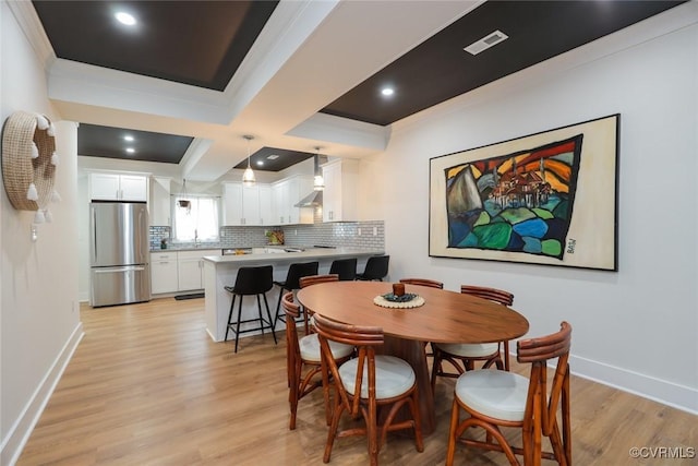 dining area featuring light wood-type flooring, baseboards, visible vents, and ornamental molding