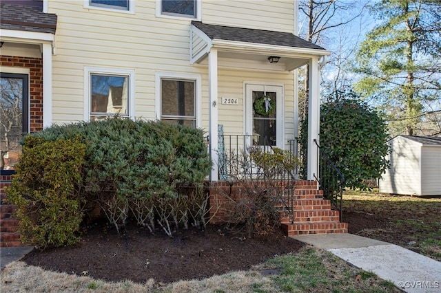 entrance to property with a porch and roof with shingles