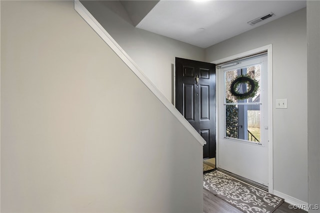 foyer with stairs, wood finished floors, visible vents, and baseboards