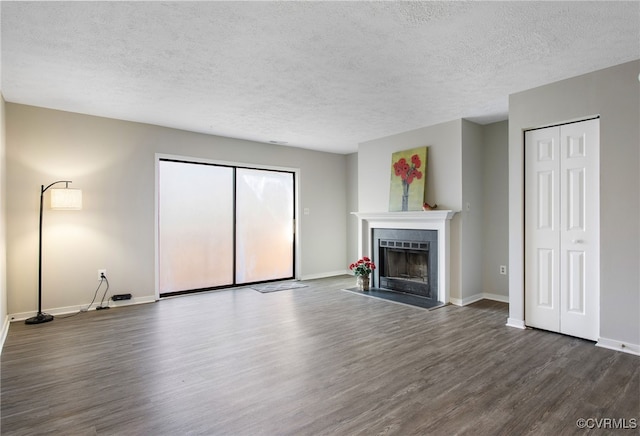 unfurnished living room with a textured ceiling, dark wood-style flooring, a fireplace, and baseboards