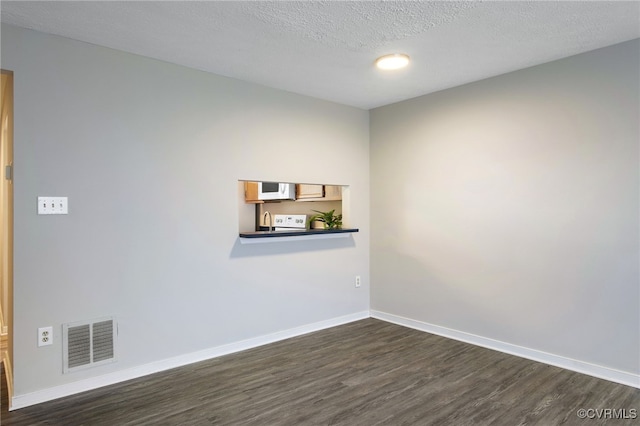 unfurnished room with baseboards, visible vents, dark wood finished floors, and a textured ceiling