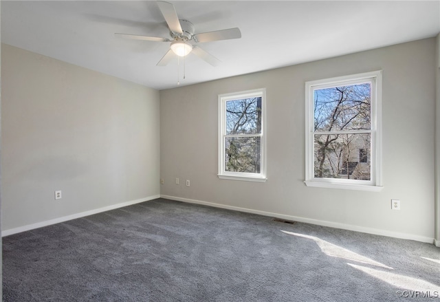 unfurnished room featuring a ceiling fan, dark carpet, visible vents, and baseboards