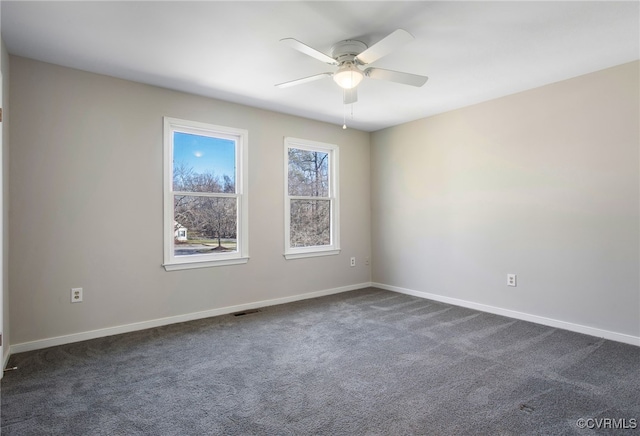 unfurnished room featuring baseboards, visible vents, dark colored carpet, and a ceiling fan