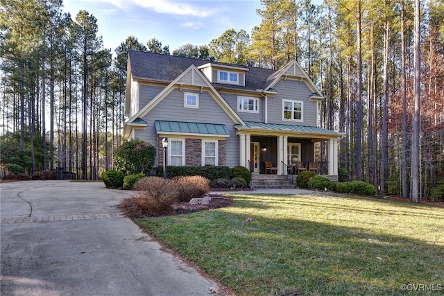 view of front of home with a porch, a standing seam roof, metal roof, stone siding, and a front lawn