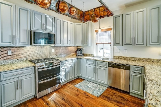 kitchen with dark wood-style flooring, stainless steel appliances, a sink, and gray cabinetry