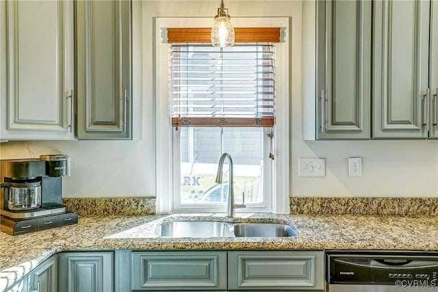 kitchen featuring dishwashing machine, a sink, a wealth of natural light, and light stone countertops