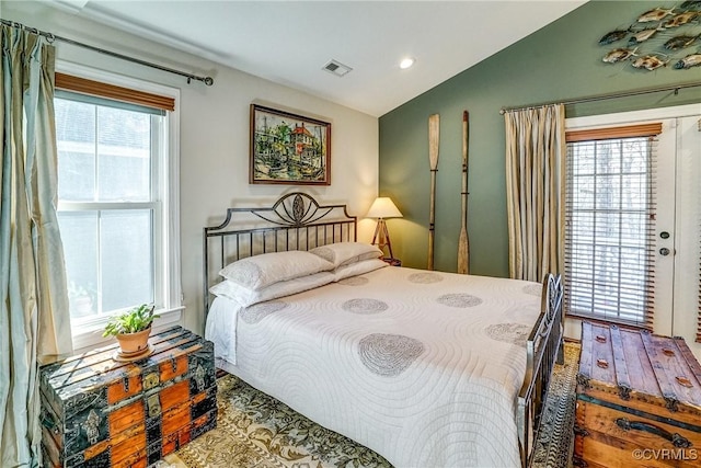 bedroom with lofted ceiling, multiple windows, visible vents, and access to exterior