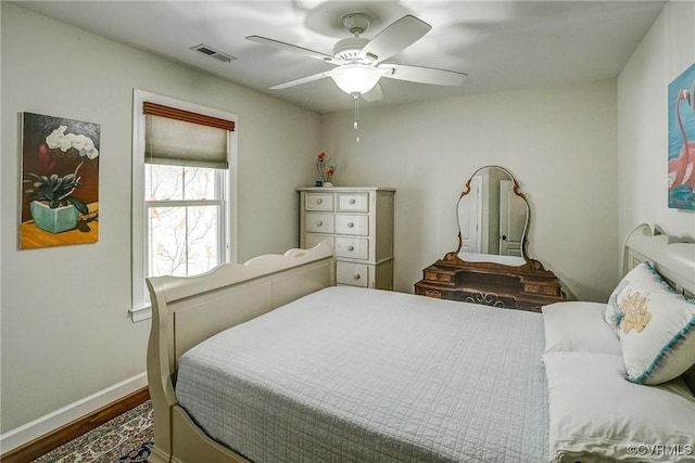 bedroom featuring visible vents, ceiling fan, baseboards, and wood finished floors