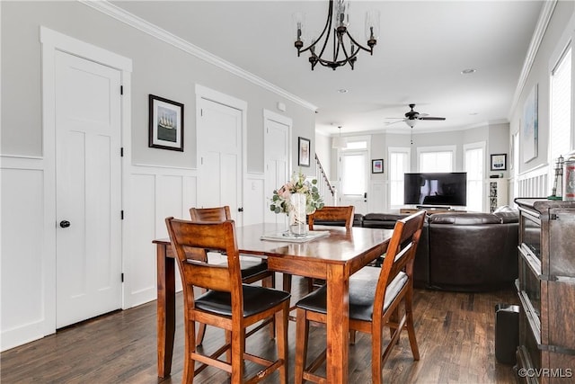 dining area with ornamental molding, dark wood-style flooring, and ceiling fan with notable chandelier