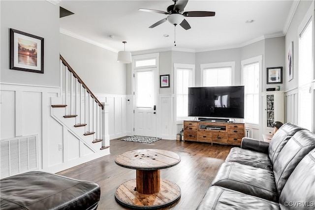 living area with stairway, wood finished floors, visible vents, and crown molding