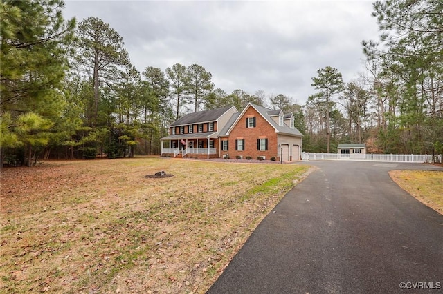 view of front of home with a garage, driveway, covered porch, a front yard, and brick siding