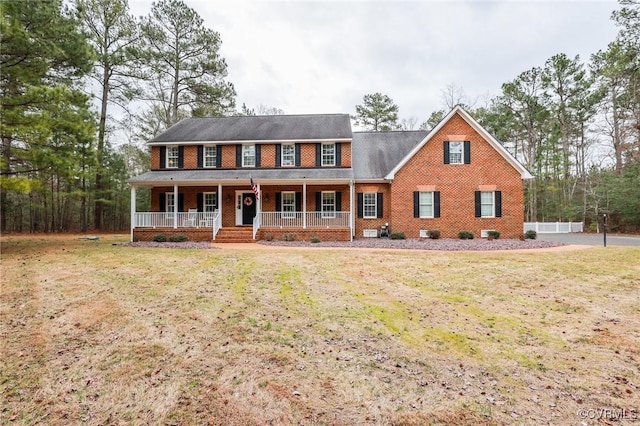 colonial home featuring a front yard, covered porch, and brick siding