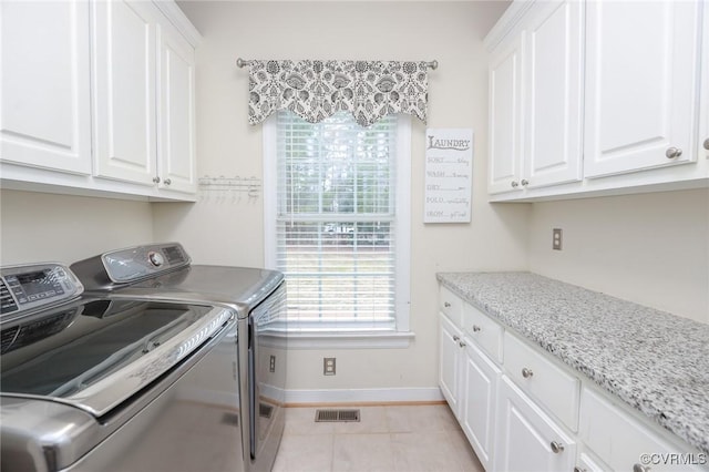 laundry area with cabinet space, light tile patterned floors, baseboards, visible vents, and washer and dryer