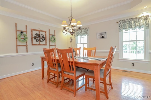 dining space with light wood finished floors, baseboards, ornamental molding, and a raised ceiling