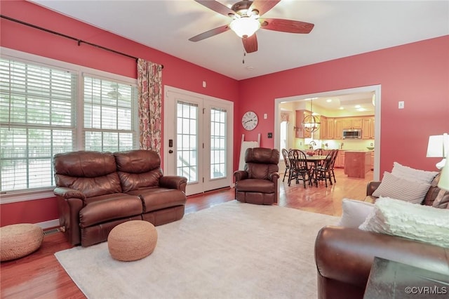 living area with light wood-style floors, visible vents, and a ceiling fan