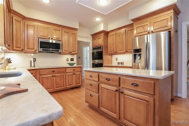 kitchen with tasteful backsplash, light wood-style flooring, stainless steel appliances, and a center island