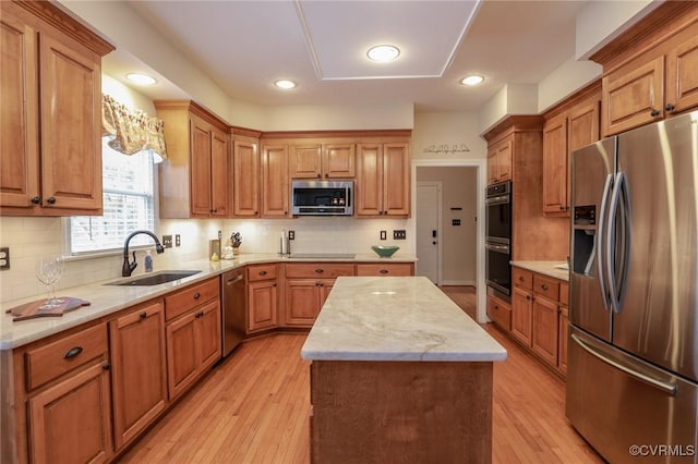 kitchen with light wood-style flooring, stainless steel appliances, a kitchen island, a sink, and decorative backsplash