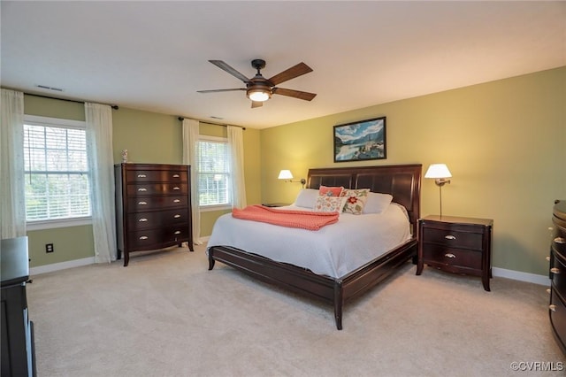 bedroom with a ceiling fan, light carpet, visible vents, and baseboards