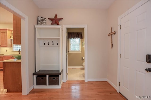 mudroom featuring a sink, light wood-style flooring, and baseboards