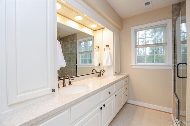 bathroom featuring a tile shower, a sink, visible vents, and baseboards