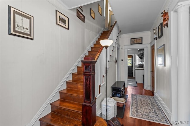 stairs with wood finished floors and crown molding