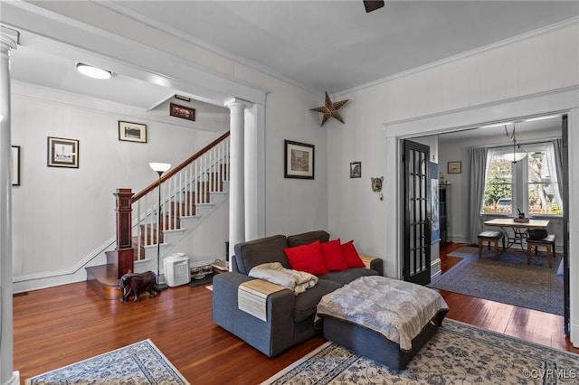 living area featuring decorative columns, wood finished floors, ornamental molding, and stairway