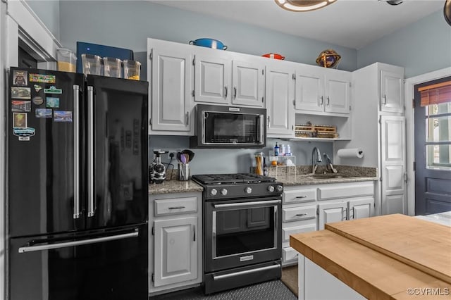 kitchen with a sink, black appliances, and white cabinetry