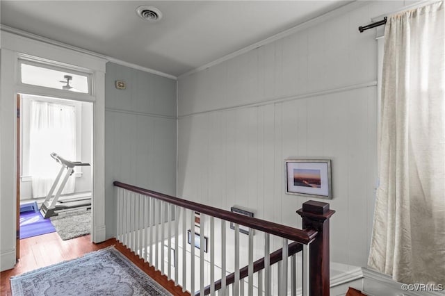 interior space with visible vents, an upstairs landing, wood finished floors, and crown molding