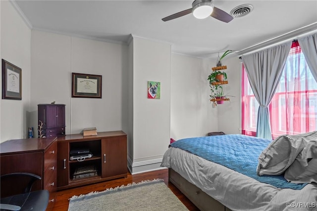 bedroom featuring wood finished floors, visible vents, and ornamental molding