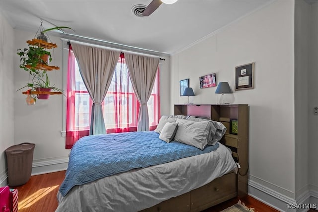 bedroom featuring visible vents, ornamental molding, baseboards, and wood finished floors