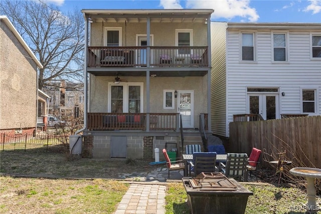 rear view of property featuring a patio, a balcony, stucco siding, french doors, and fence private yard