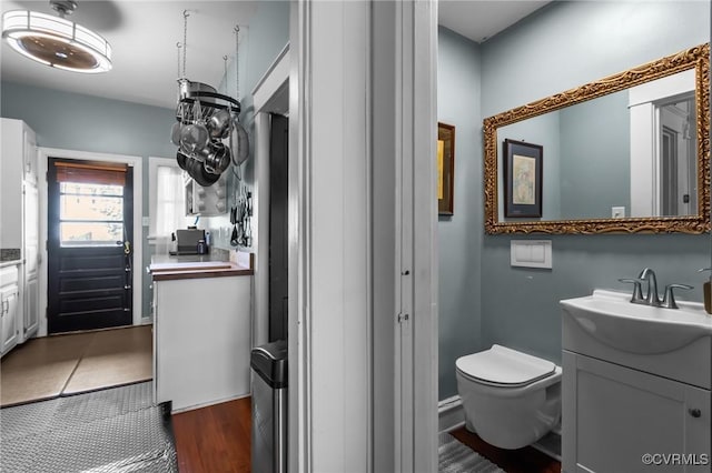 bathroom with toilet, vanity, and wood finished floors