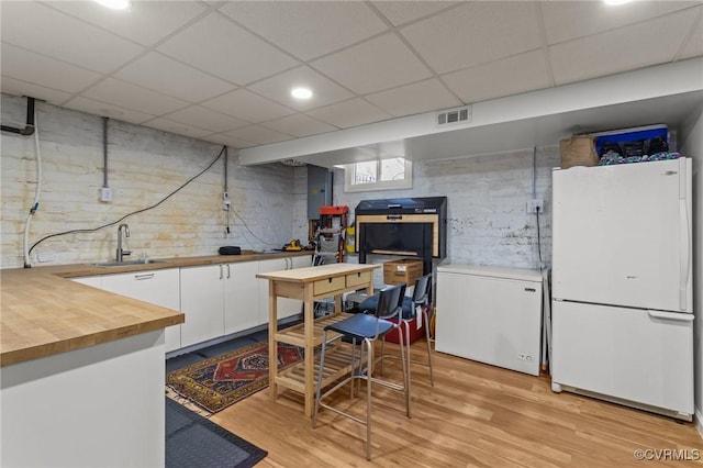 kitchen with visible vents, butcher block counters, freestanding refrigerator, refrigerator, and a sink