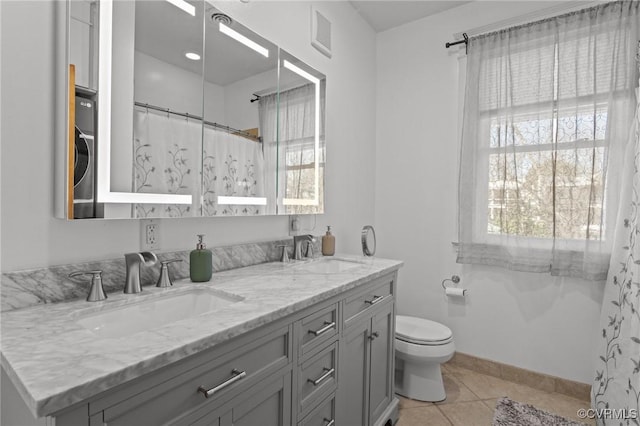 bathroom featuring tile patterned floors, double vanity, toilet, and a sink