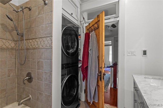 clothes washing area with a sink, laundry area, and stacked washing maching and dryer