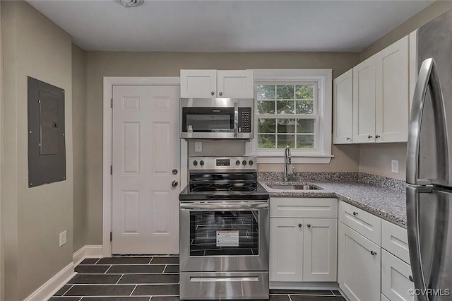 kitchen featuring a sink, white cabinetry, baseboards, appliances with stainless steel finishes, and electric panel