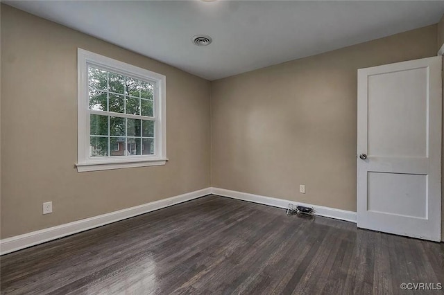 spare room featuring visible vents, dark wood finished floors, and baseboards