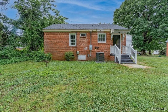 rear view of house with brick siding, a yard, and central air condition unit