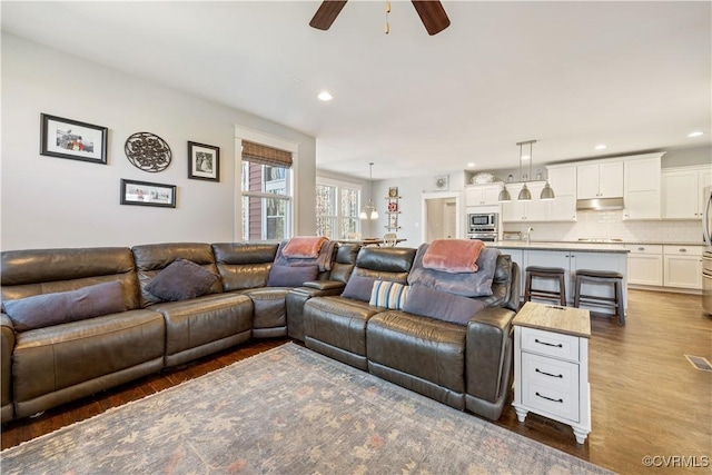 living area with a ceiling fan, wood finished floors, and recessed lighting